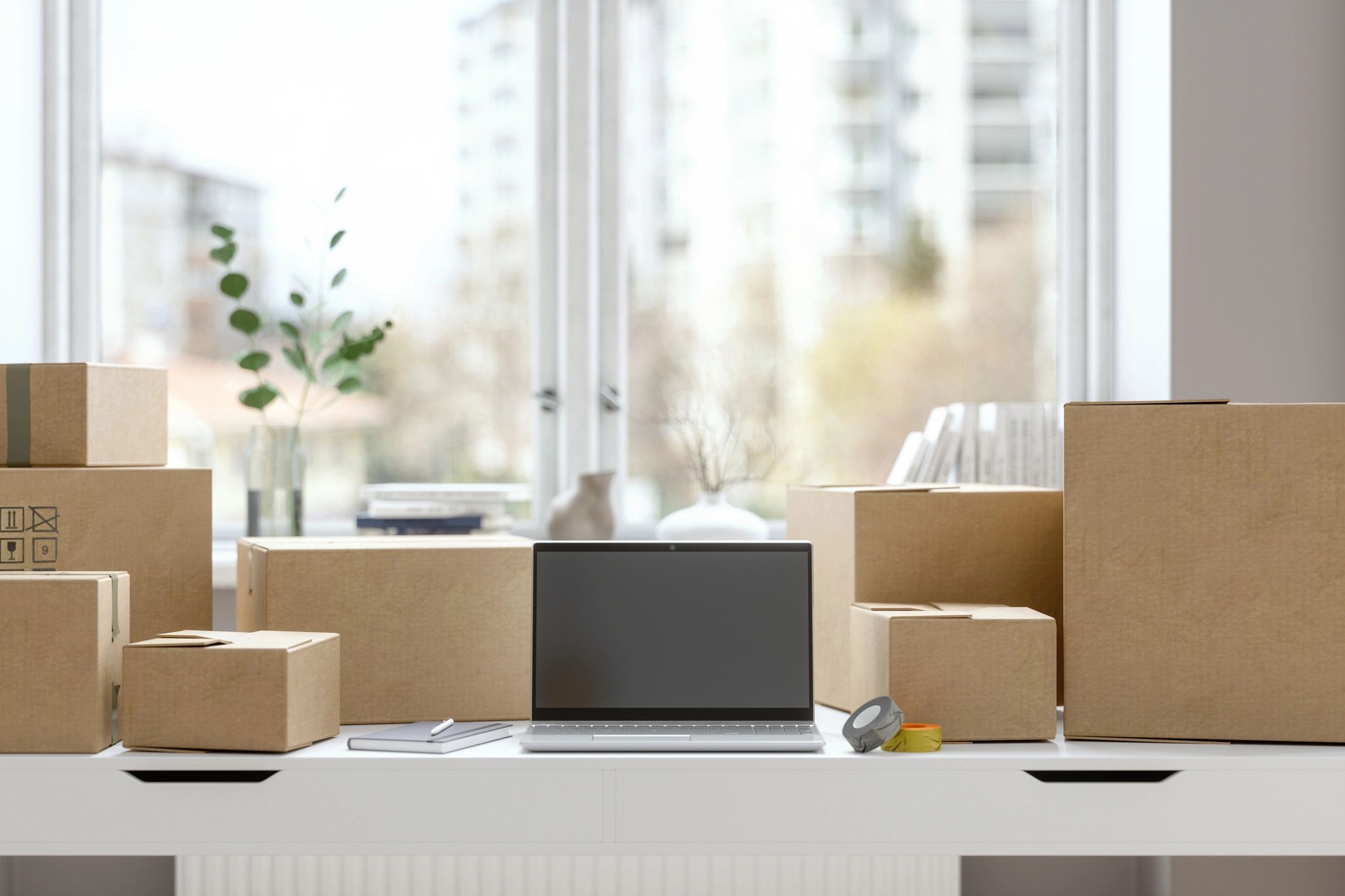 Laptop on a desk with packaging supplies, representing device sales and delivery